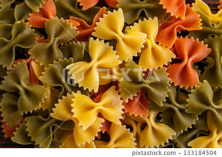 Colorful farfalle pasta on a wooden table, top view of delicious Italian durum wheat pasta Colorful farfalle pasta on a wooden table, top view of delicious Italian durum wheat pasta 133184504