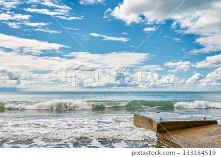An old pier against a stormy sea with a cloud-covered horizon, a seascape symbolizing the fickleness and power of the elements, a backdrop for advertising natural seafood 133184519