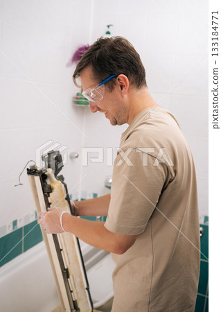 Positive professional HVAC technician man cleaning dirty air conditioner parts with detergent, ensuring proper hygiene and improved air quality. Concept of air condition maintenance service. 133184771