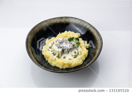 Mashed potatoes with creamy mushroom sauce in black bowl, minimal white background, top view Mashed potatoes with creamy mushroom sauce in black bowl, minimal white background, top view 133185520