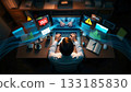 Navigating the complex digital landscape. A man seated at a desk works on a laptop, surrounded by digital projections displaying graphs, warnings, and numbers. 133185830