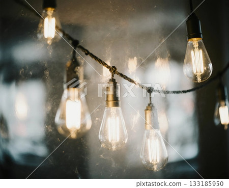 Warm glow from garland light bulbs hangs in clusters, illuminating a cozy indoor space. Shadows and reflections enhance the evening atmosphere, adding charm Generative AI 133185950