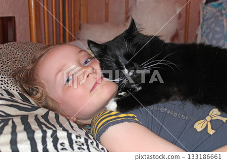 Little girl laying in bed together with her cat. Together with your pet Little girl laying in bed together with her cat. Together with your pet 133186661