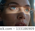Vision of the future reflected in her eyes. Close-up of a woman's face focusing on her blue eyes, which reflect futuristic structures like sleek buildings and spacecraft.  133186909