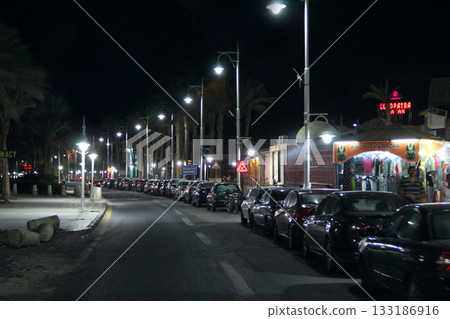 View of night street of Hurghada with lanterns and cars. Night lighting in city View of night street of Hurghada with lanterns and cars. Night lighting in city 133186916