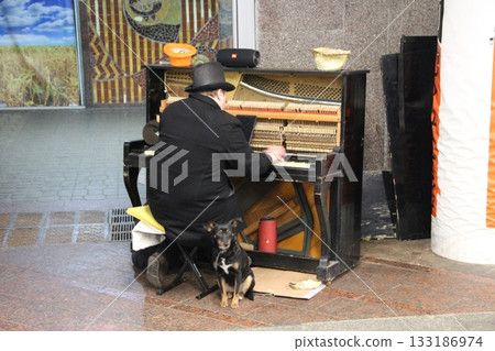 Homeless man playing piano on street surrounded by stray dogs Homeless man playing piano on street surrounded by stray dogs 133186974
