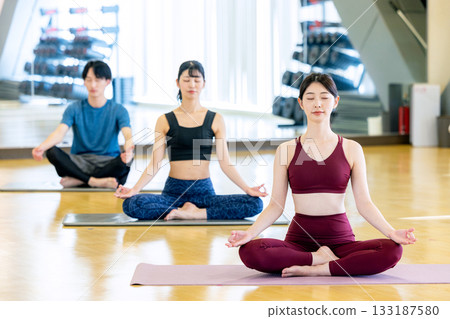 Young men and women practicing yoga in a yoga studio 133187580