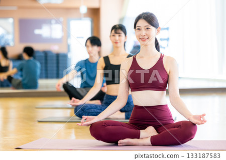 Young men and women practicing yoga in a yoga studio Young men and women practicing yoga in a yoga studio 133187583