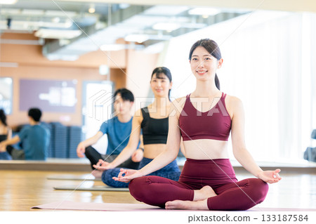 Young men and women practicing yoga in a yoga studio Young men and women practicing yoga in a yoga studio 133187584