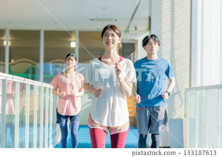 Men and women running on an indoor track 133187613