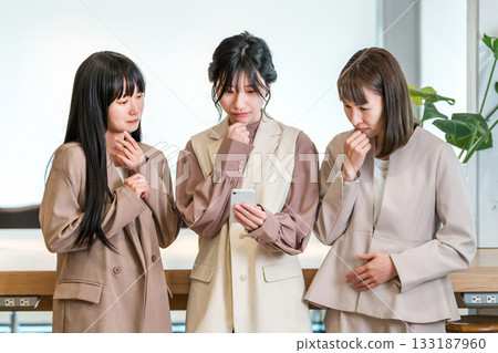 Businesswoman boss and subordinate worried about looking at smartphone 133187960