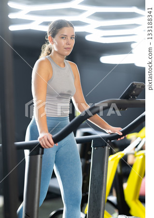 Young woman doing cardio exercises on treadmill Young woman doing cardio exercises on treadmill 133188341