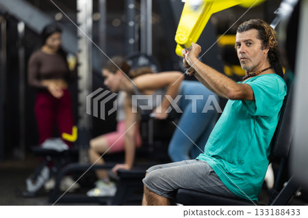 Determined middle-aged man training upper body muscles 133188433