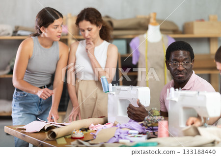 Multiethnic participants in coterie practice sewing, chatting, work textile and paper dress pattern Multiethnic participants in coterie practice sewing, chatting, work textile and paper dress pattern 133188440