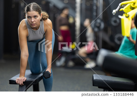 Young woman doing exercises with dumbbells in the gym Young woman doing exercises with dumbbells in the gym 133188446