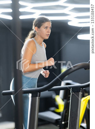 Young woman doing cardio exercises on treadmill Young woman doing cardio exercises on treadmill 133188457