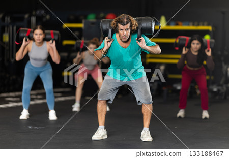 Active man doing a squat with a bag on his back Active man doing a squat with a bag on his back 133188467