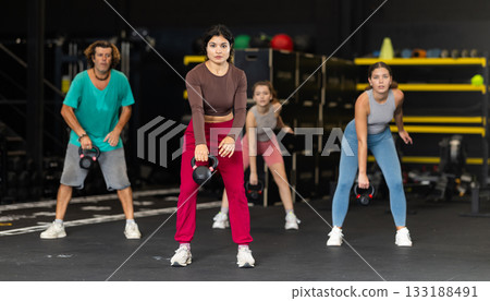 Latina woman doing kettlebell exercises against the background of people exercising 133188491