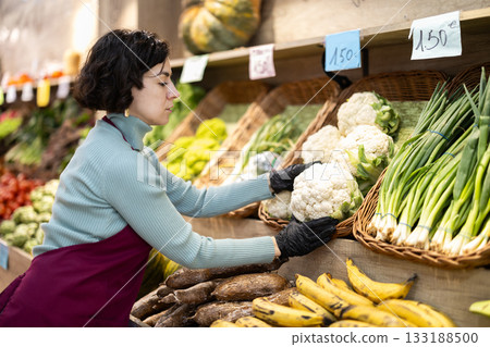 Adult woman seller puts cauliflower on display Adult woman seller puts cauliflower on display 133188500