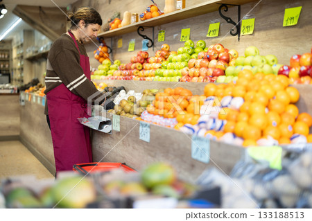 Adult man seller putting champignons in vegetable shop Adult man seller putting champignons in vegetable shop 133188513