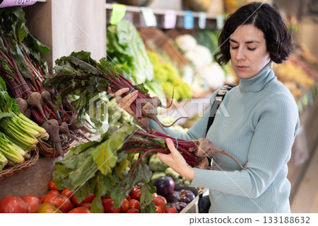 Adult woman chooses beets in vegetable shop Adult woman chooses beets in vegetable shop 133188632