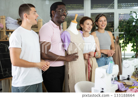 Positive attendees of dressmaking courses standing by mannequin Positive attendees of dressmaking courses standing by mannequin 133188664