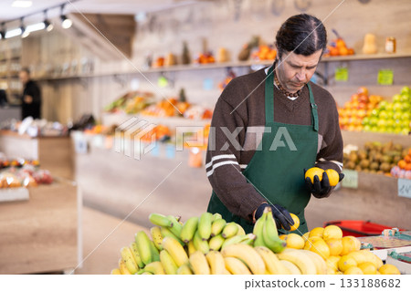 Adult woman seller puts lemons on display Adult woman seller puts lemons on display 133188682