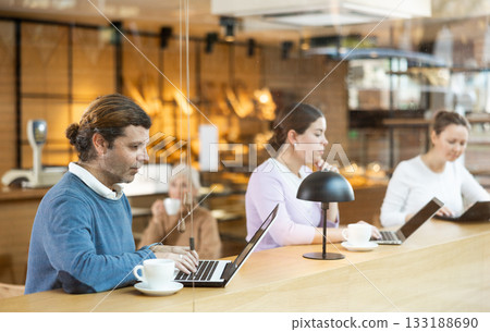Focused man browsing websites on laptop and drinking coffee in cafe Focused man browsing websites on laptop and drinking coffee in cafe 133188690