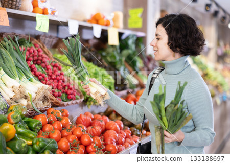 Female shopper choosing leek at supermarket counter 133188697