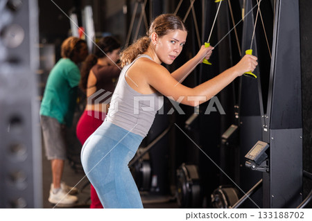 Woman doing exercises on ski ergometer simulator 133188702