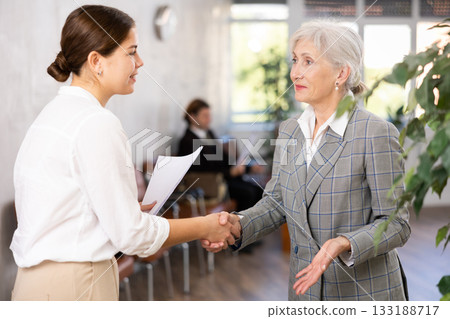 Young businesswoman shaking hands with senior woman executive Young businesswoman shaking hands with senior woman executive 133188717