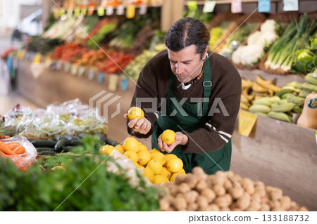 Adult woman seller puts lemons on display Adult woman seller puts lemons on display 133188732