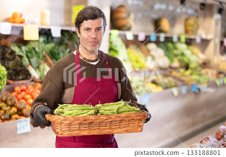 Adult man seller with basket of green peas Adult man seller with basket of green peas 133188801