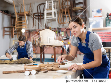 Restorer woman carefully cleans dirt and dust from carved wooden decor element 133188818