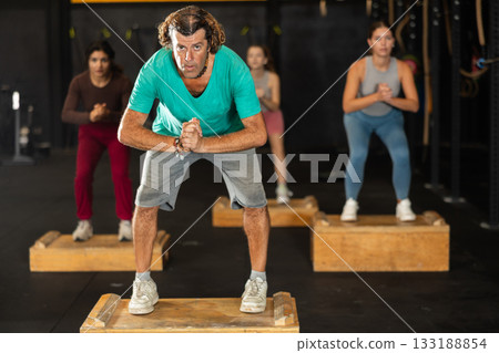 man at a Crossfit training steps on a box man at a Crossfit training steps on a box 133188854
