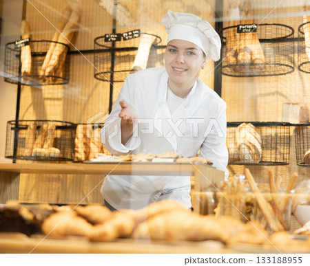 Young female baker presenting fresh baked products 133188955