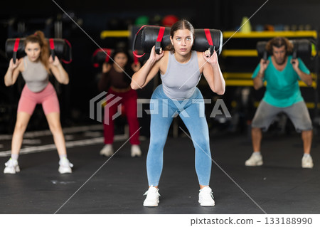 Young woman doing exercises with a bag in the gym Young woman doing exercises with a bag in the gym 133188990