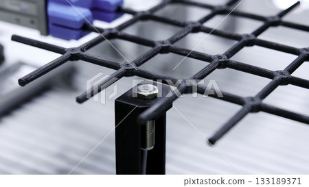 Robotic arm picking up black plastic grid structure. Media 133189371