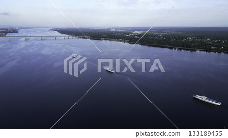 Tugboat pushing barge on wide river near bridge. Clip 133189455