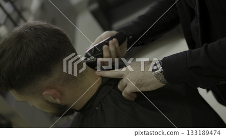 Professional barber giving haircut with electric clipper. Clip 133189474