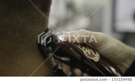 Barber giving a man haircut with electric clipper. Clip Barber giving a man haircut with electric clipper. Clip 133189498