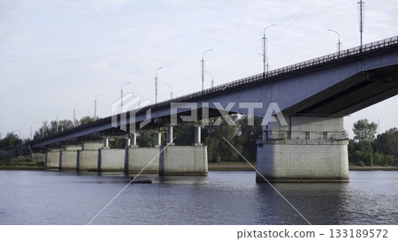 Small fishing boat cruising under a large concrete bridge over a river. Clip Small fishing boat cruising under a large concrete bridge over a river. Clip 133189572