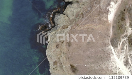 Aerial top down view of rocky shore and turquoise ocean. Media Aerial top down view of rocky shore and turquoise ocean. Media 133189789