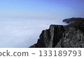 Rocky mountain cliff emerging above flowing clouds. Media 133189793