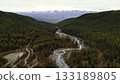 River flows through lush valley beneath snow capped mountains. Media 133189805