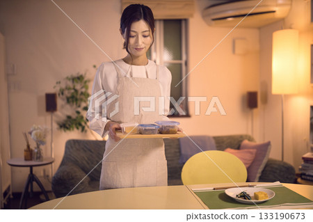 中年婦女端著晚餐走向餐桌。 133190673