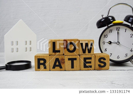 LOW RATES alphabet letters with house model, alarm clock and magnifying glass on wooden background 133191174