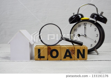 LOAN alphabet letters with house model, alarm clock and magnifying glass on wooden background 133191176