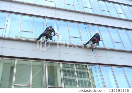 Workers cleaning windows in a high-rise building 133191326