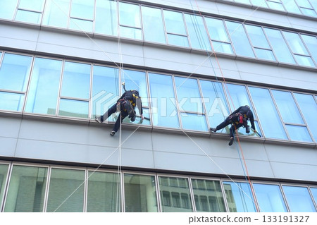 Workers cleaning windows in a high-rise building 133191327